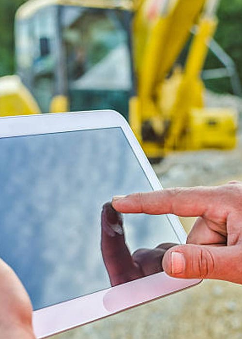 Close-up of a field supervisor using a digital tablet for real-time daily production reporting at an underground utility construction site